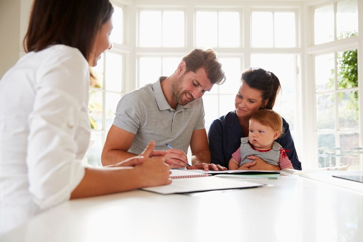 A family sitting at the table with papers and a baby.